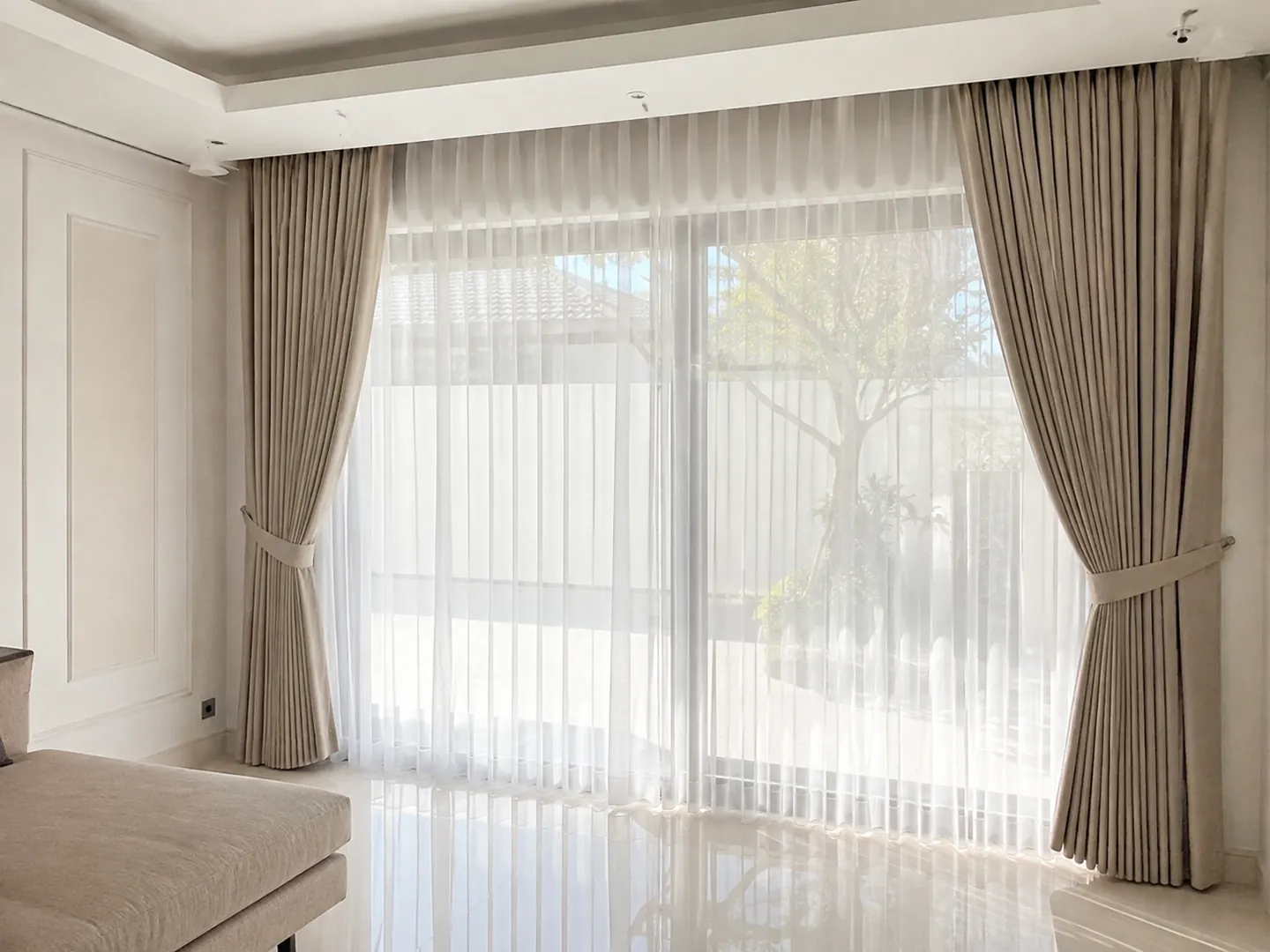 Gorden beige dan vitrase putih pada bukaan kaca lebar