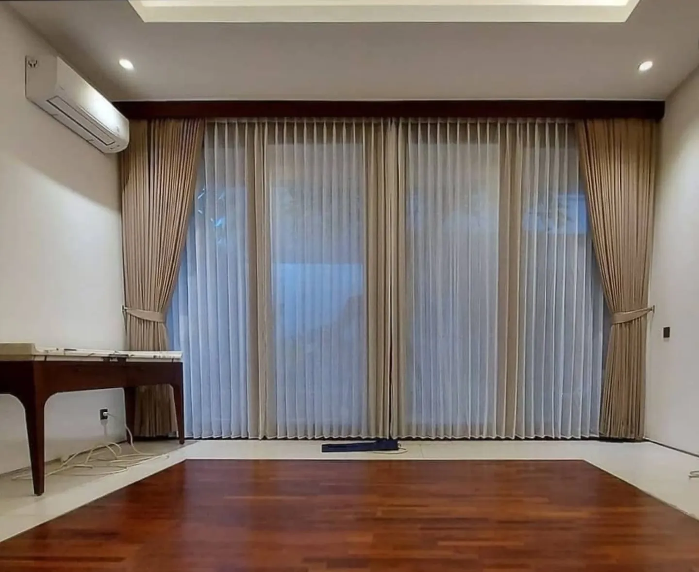 Gorden beige dengan vitrase putih pada area jendela lebar