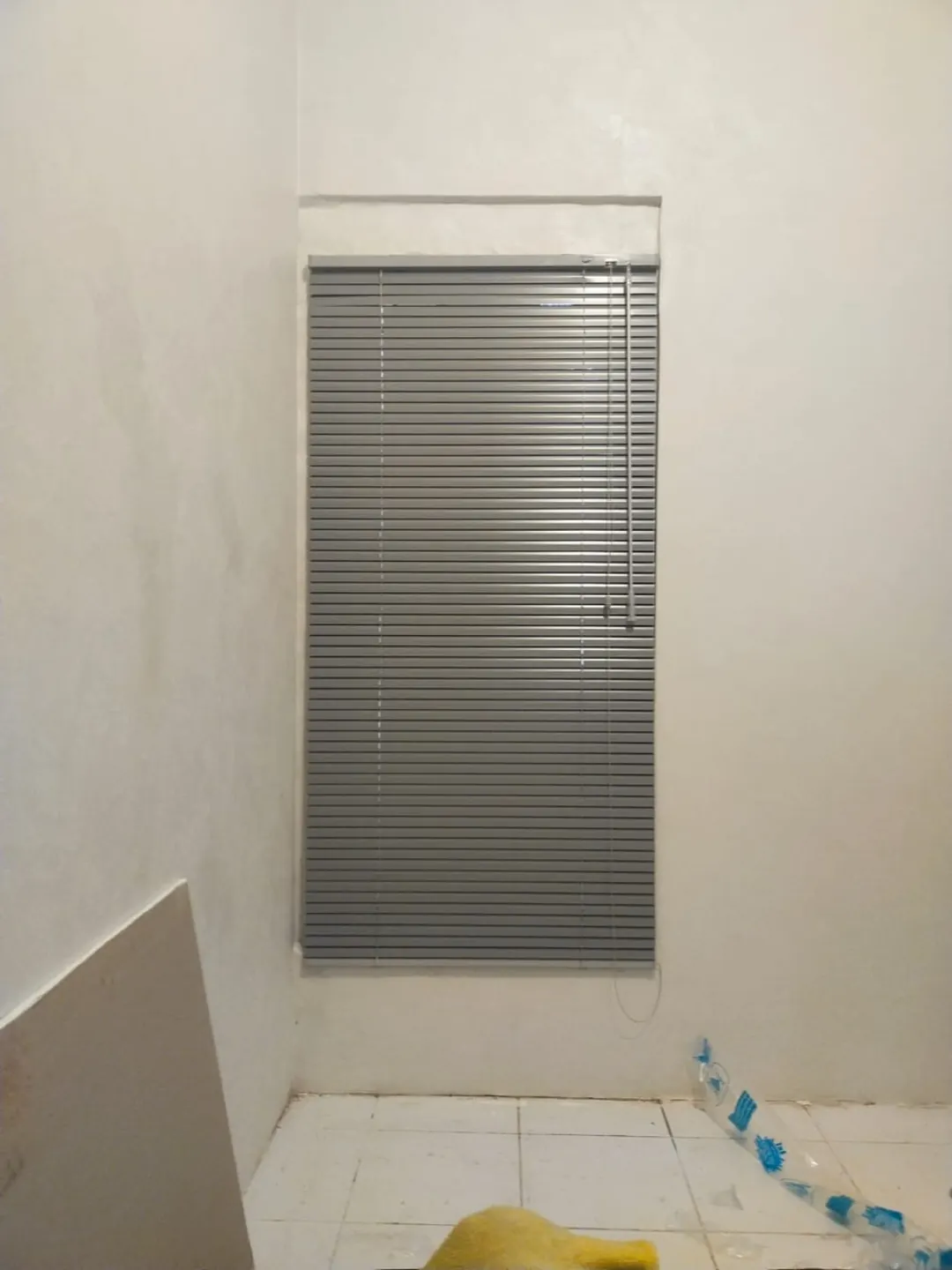 Horizontal blind abu-abu terpasang pada jendela sempit